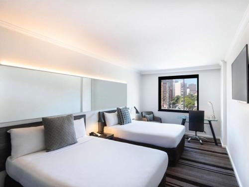 a hotel room with two beds and a couch at Mercure Sydney in Sydney