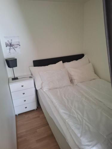 a bedroom with a white bed and a night stand at Oppheim apartment, shared Pool & Sauna in Vossevangen