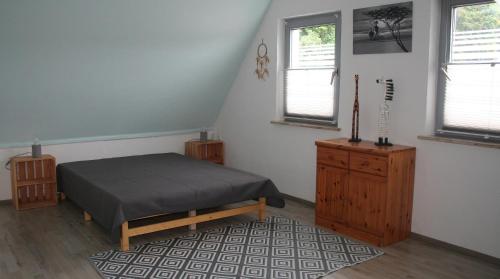 a bedroom with a bed and a dresser and two windows at Ferienwohnung Hexenhäusla in Gößweinstein