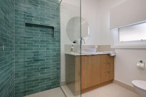 a bathroom with a shower with a sink and a mirror at Delightful Digs on David in Albury