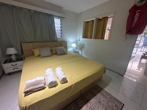 a bedroom with a yellow bed with towels on it at The KentiGate - much more than a room in Nuku‘alofa