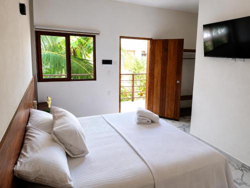 a bedroom with a white bed with a television on the wall at Hotel Céntrico Tulum in Tulum