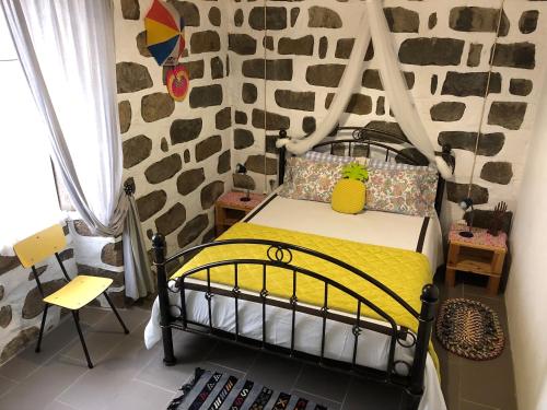a bedroom with a bed in a room with a rock wall at Casa Auri in Faial da Terra