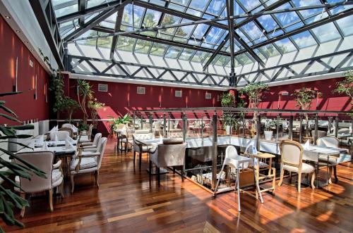 un restaurante con mesas y sillas y techo de cristal en Hotel Czarny Potok Resort SPA & Conference, en Krynica-Zdrój