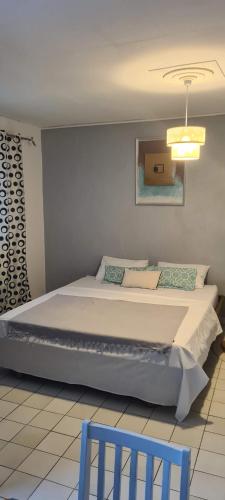 a bedroom with a large bed with two blue chairs at Paradies Caraïbes I in Les Abymes