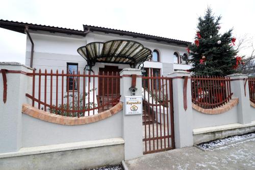 a christmas tree in front of a house with a gate at Rapsodia Pension in Suceava