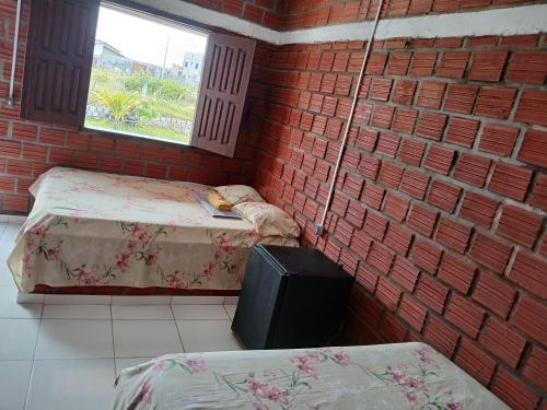 a room with two beds and a brick wall at Chalé 02 Cantinho do Céu- Santo Amaro do MA in Santo Amaro