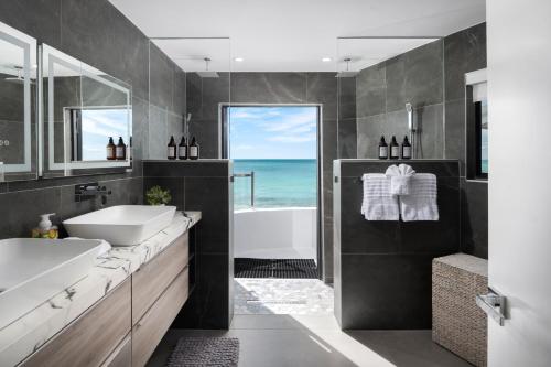 a bathroom with two sinks and a tub and a window at Opaline Villa 4BR 2Bath-Ocean Front in Providenciales