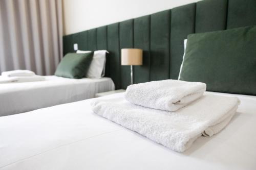 a pile of towels sitting on top of a bed at O Vilarealense Heritage Apartment in Vila Real