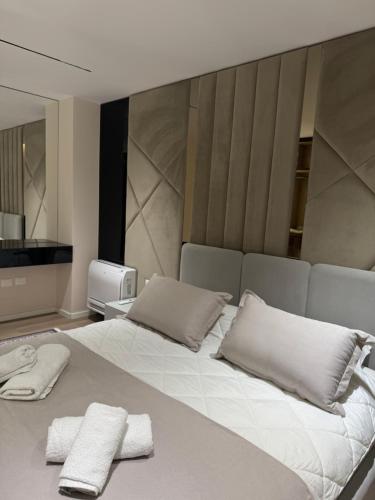 a bedroom with a large white bed with towels on it at Modern Lake Apartment Tirana - Quiet Stay near Liqeni i Thatë in Tirana