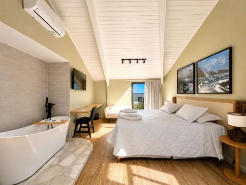 a bedroom with a large bed and a bath tub at Luna Hotel Boutique - Frente à Praia in Guarujá