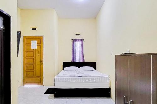 a bedroom with a bed and a wooden door at RedDoorz at Morowali Sulawesi Tengah in Ulunipa