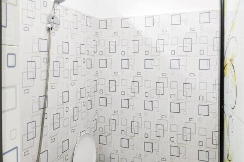 a bathroom with a white wall with a shower at RedDoorz at Morowali Sulawesi Tengah in Ulunipa