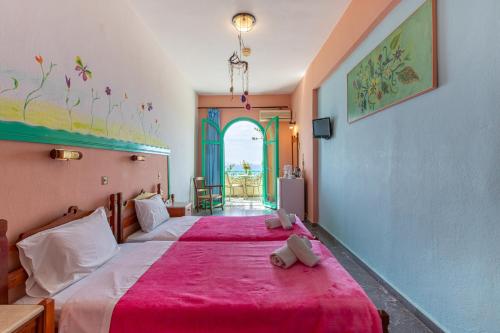 a bedroom with two beds with pink sheets at Erofili Rooms in Agia Galini