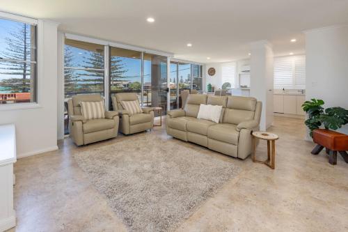a living room with two couches and a table at Beach Street Oasis - Tuncurry in Tuncurry