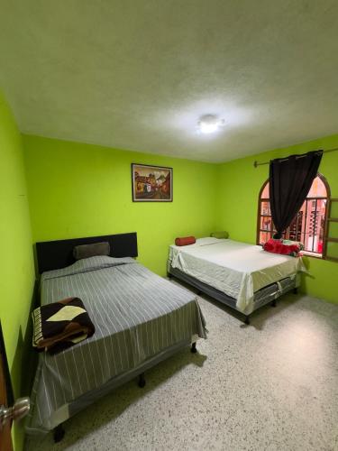 two beds in a room with green walls at Casa Nimacachi in Panajachel