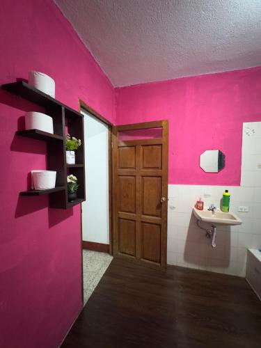 a pink bathroom with a sink and a door at Casa Nimacachi in Panajachel