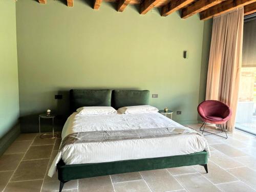 a green bedroom with a bed and a red chair at Elegant suite with porch and shared pool in Adro