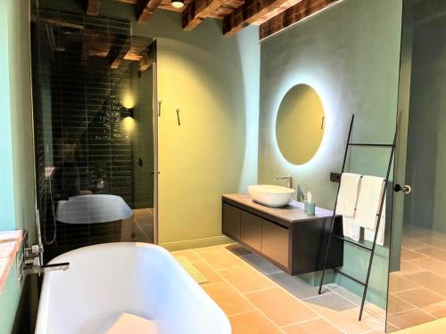 a bathroom with a tub and a sink and a mirror at Elegant suite with porch and shared pool in Adro