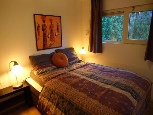 a bedroom with a bed and two lamps and a window at Vechtdal Chalet de Eik in Rheezerveen