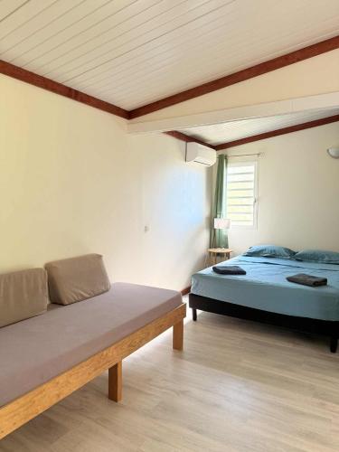 a bedroom with a bed and a bench in it at Auberge de Poé in Bourail