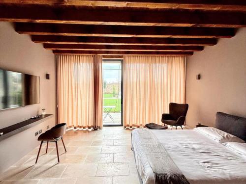 a bedroom with a bed and two chairs and a large window at Elegant suite with shared pool in Adro