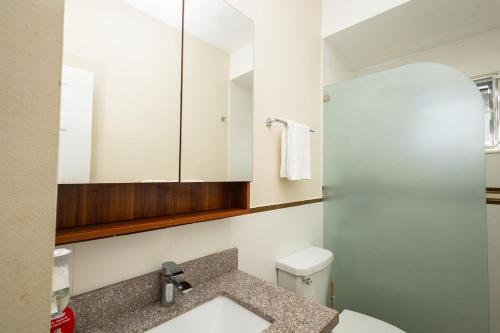 a bathroom with a toilet and a sink and a mirror at Oceanpointe Luxury Retreat-3 Bedroom Home in Point