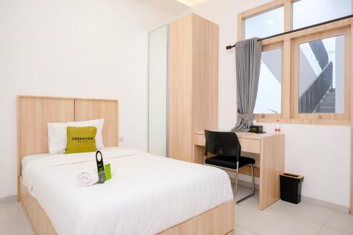 a bedroom with a bed and a desk with a bottle of wine at Urbanview Hotel Subali Purwokerto in Purwokerto