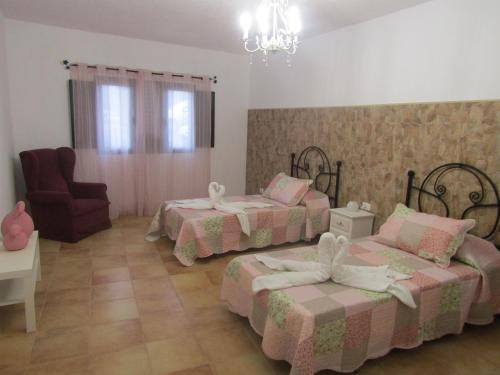 a bedroom with two beds and a chair and a chandelier at La Casita Villalba in Arrieta