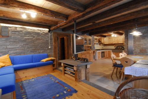 a living room with a blue couch and a kitchen at Haus Khlemele in Sauris