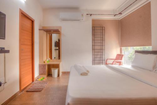 a bedroom with a large white bed and a window at Kolam Serviced Apartments - Adyar. in Chennai