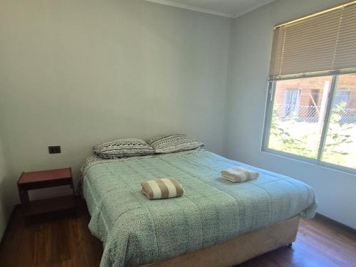 a bedroom with a bed with two pillows and a window at cabañas don Jose in Pucón