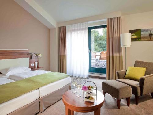 ein Hotelzimmer mit einem Bett, einem Stuhl und einem Tisch in der Unterkunft Mercure Tagungs- & Landhotel Krefeld in Krefeld