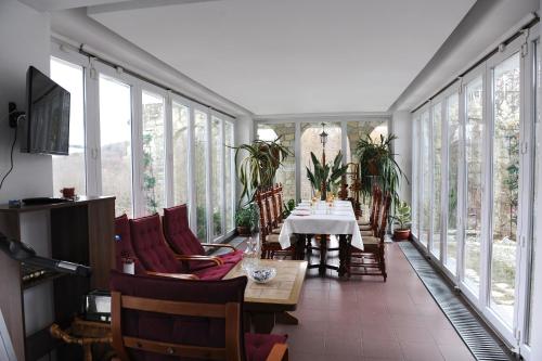 a dining room with a table and chairs and windows at Rapsodia Pension in Suceava