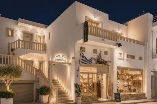 a white building with stairs in front of a store at Hotel Dionysis Studios in Adamantas