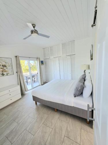 a white bedroom with a bed and a ceiling fan at Swan cottages #6 Waterfront in Providenciales