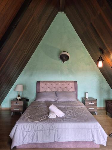 a bedroom with a large bed with a pointed ceiling at Orchid Chalet in Ringlet