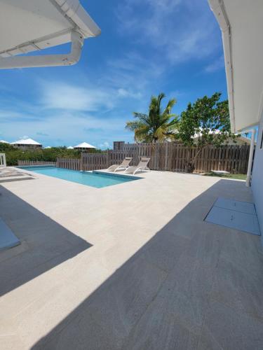 a patio with a pool and a wooden fence at Swan Cottages #5 Waterfront in Providenciales