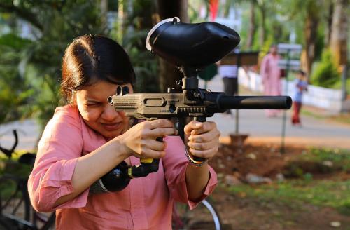 a woman is holding a gun in a field at Vythiri Village in Vythiri