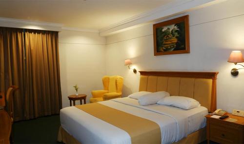 a hotel room with a bed and a yellow chair at Harmoni Suites Hotel in Nagoya