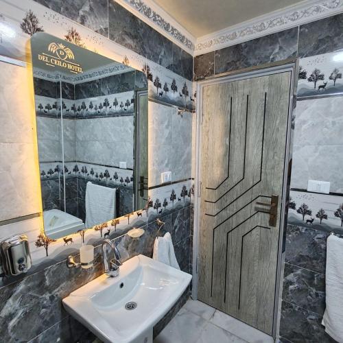 ein Badezimmer mit Waschbecken, Spiegel und Tür in der Unterkunft Dell Celio Hotel in Kairo