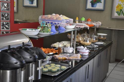 a buffet line in a kitchen with food on it at Imperial Hotel in Juiz de Fora