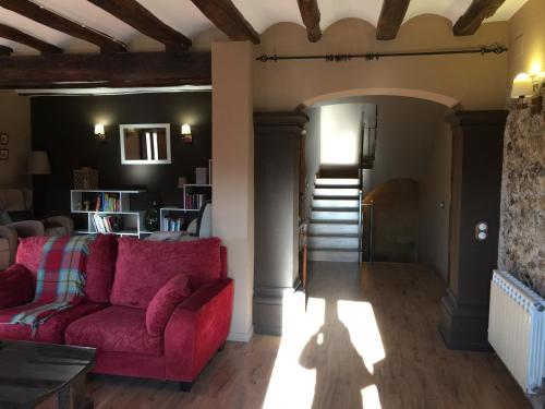 a living room with a red couch and stairs at La Masia del Batlle in Sarroqueta