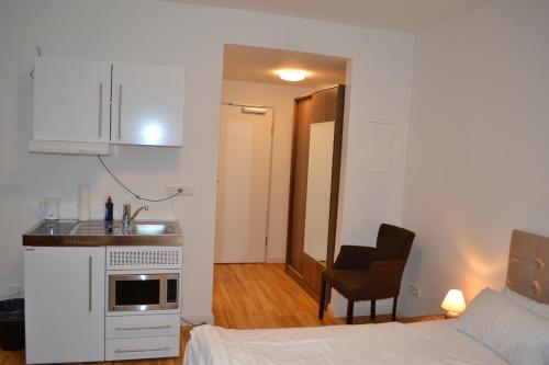 ein Schlafzimmer mit einem Bett und einem Schreibtisch sowie eine Küche in der Unterkunft M&A Cityapartments Hildesheim in Hildesheim