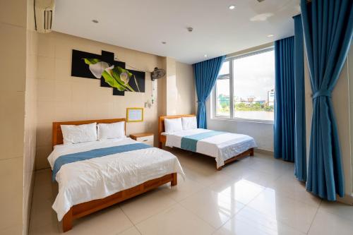a bedroom with two beds and a window at Khách sạn SIC Quảng Bình in Dong Hoi