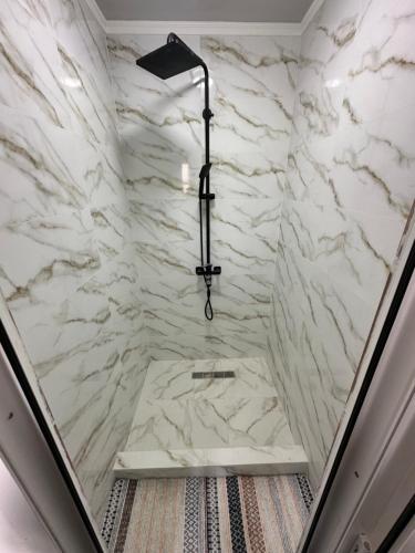 a bathroom with a shower with marble walls at Gulazyk guest house in Bokonbayevo