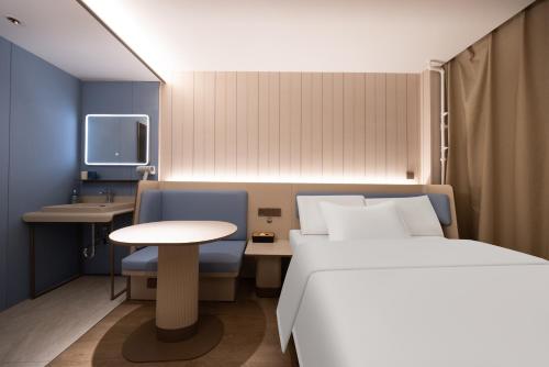 a bedroom with a bed and a table and a tv at Hanting Hotel Beijing Xizhimen in Beijing