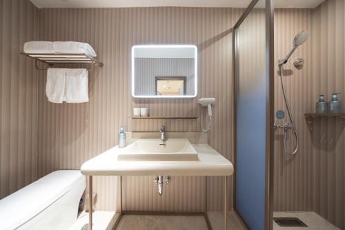 a bathroom with a sink and a shower at Hanting Hotel Beijing Xizhimen in Beijing