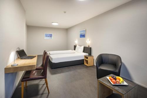 OberentfeldenにあるAparthotel-aarau-WEST Swiss Qualityのベッド、デスク、椅子が備わるホテルルームです。