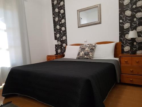 a bedroom with a black and white bed and a mirror at Casa do Cabo de Santa Maria in Sagres